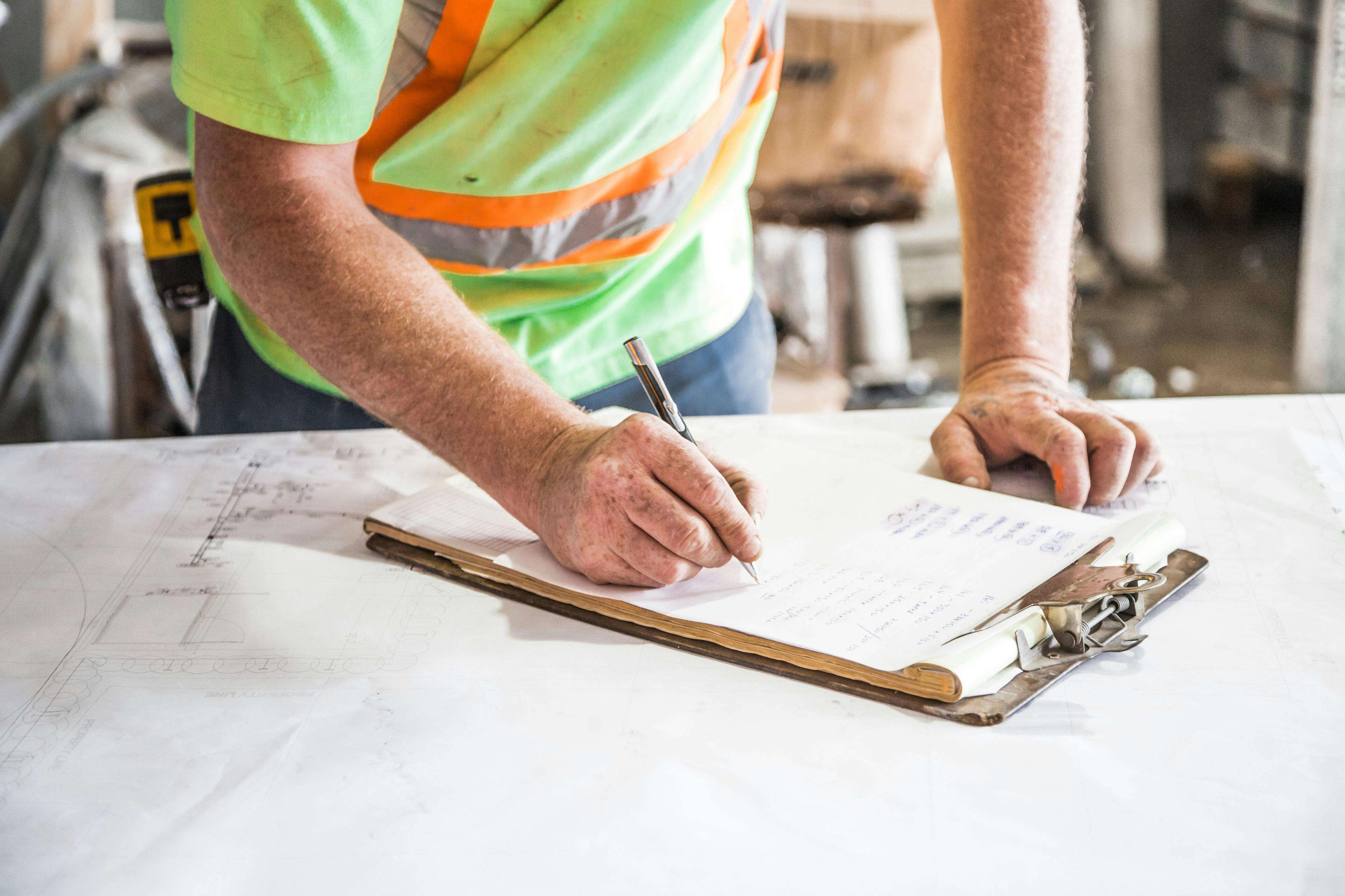 Building inspector recording findings on a clipboard at a construction site