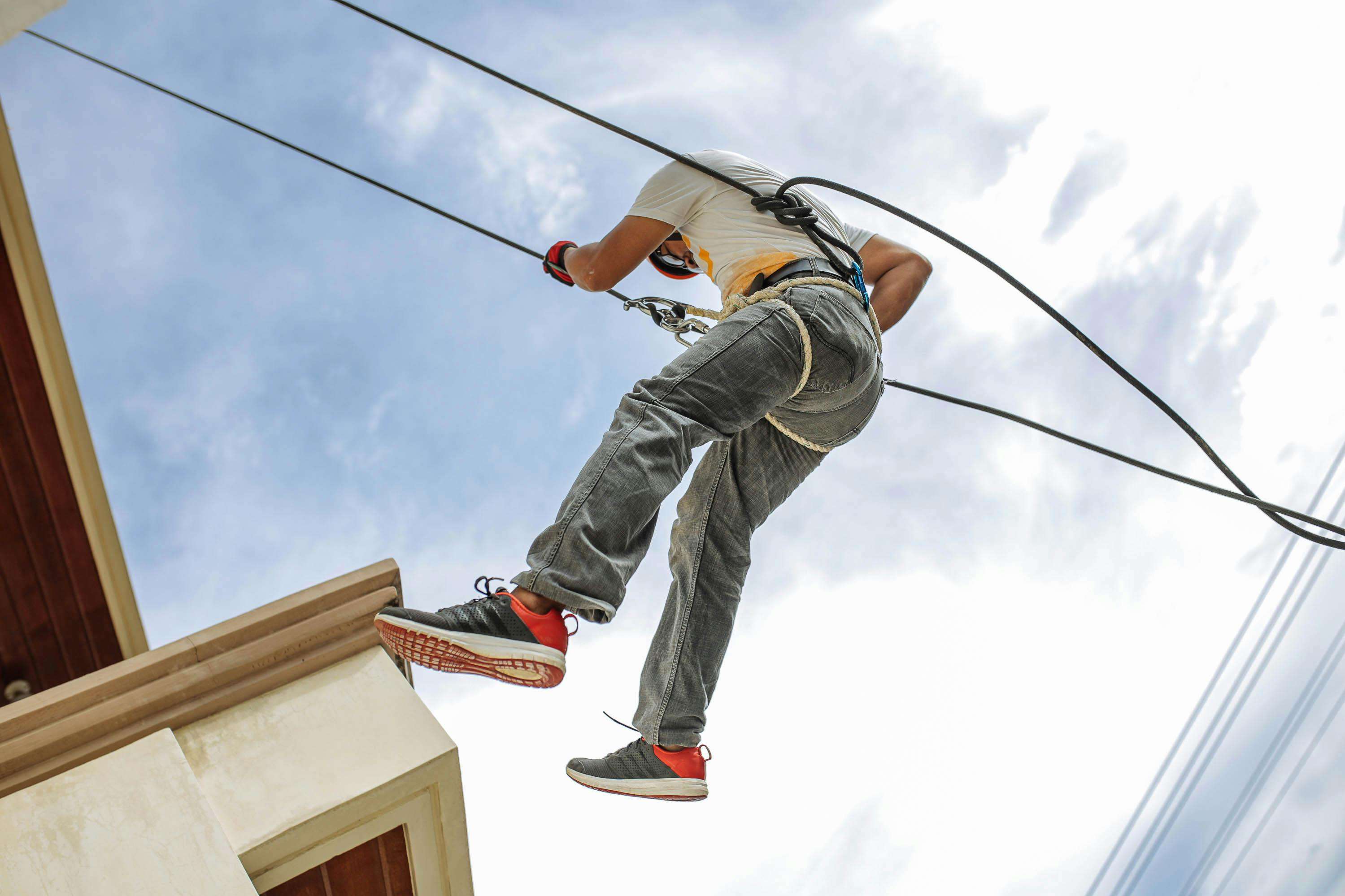 Rope access technician rappelling down a building for bird proofing installation