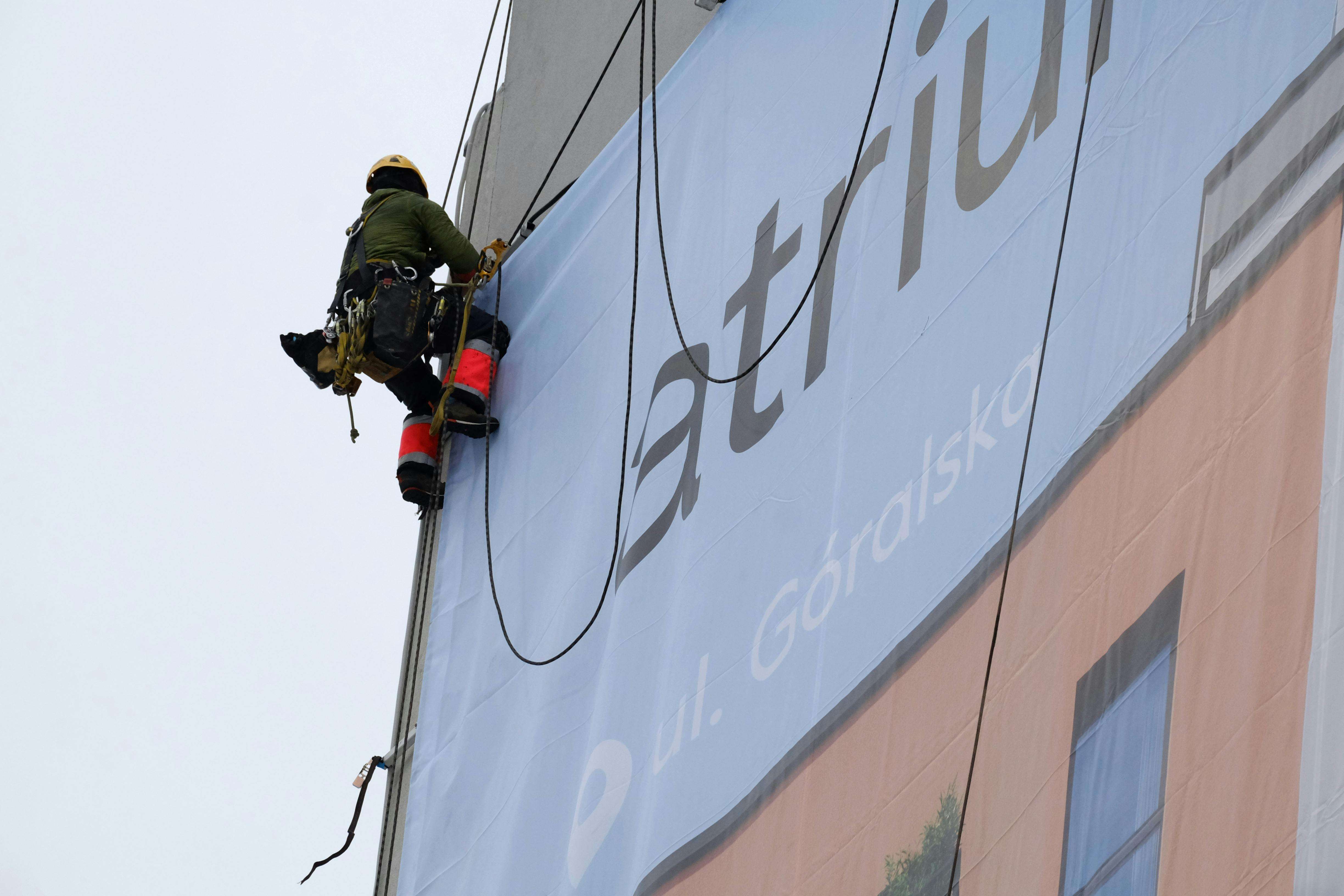 Rope access worker installing a banner on a building exterior