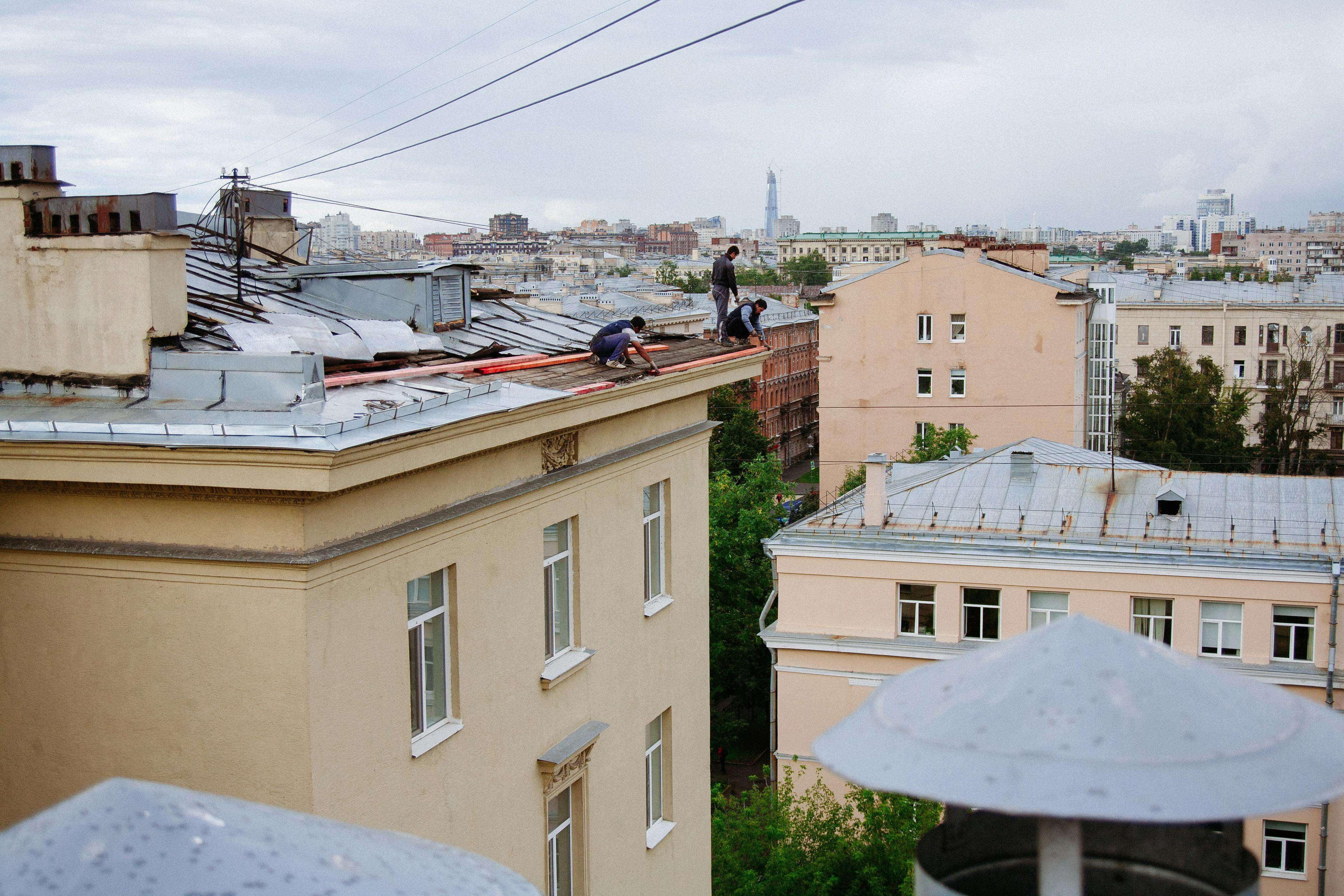 Workers on a rooftop carrying out gutter and drainage maintenance